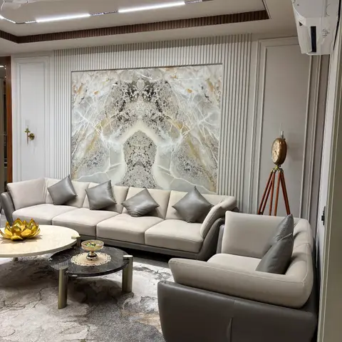 Living room with a book-matched onyx slab feature wall flanked by fluted panelling, a beige leather sofa with grey cushions