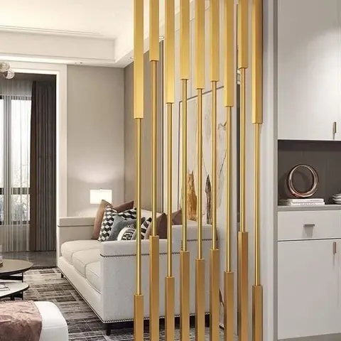 Living room with a brass vertical-rod partition screen dividing the entrance console from a cream nailhead-trim sofa and layered rugs.
