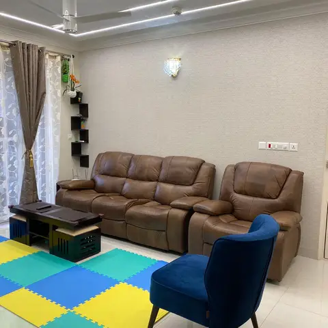 Living room with a brown leather reclining sofa set and a navy velvet accent chair against a textured wallpaper wall