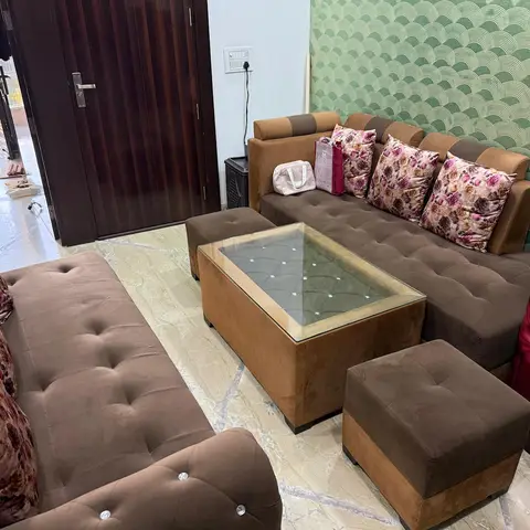 Living room with a brown tufted sofa set and floral cushions beside the main entry door, a scalloped-pattern green wallpaper on the side wall