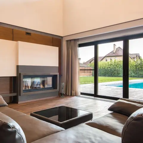 Living room with a built-in linear fireplace set into a two-tone wood accent wall, brown leather sofas around a glass coffee table