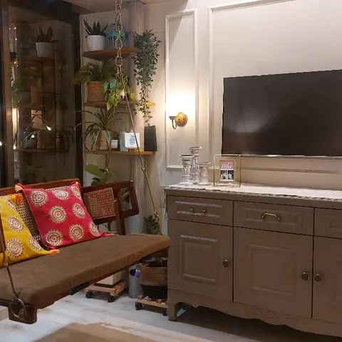 Living room with a cane-sided wooden hanging swing styled with yellow and red medallion-print cushions