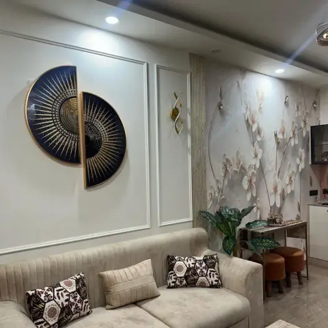 Living room with a channel-tufted beige sofa against a wall of raised moulding panels, a circular gold-and-navy sunburst wall sculpture