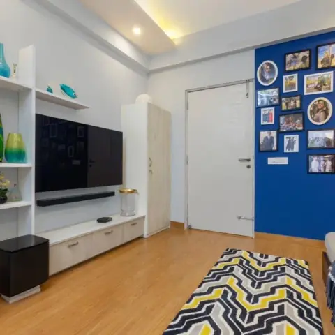 Living room with a cobalt-blue wall covered in a family photo gallery, a wall-mounted TV and soundbar over a pale-oak drawer console