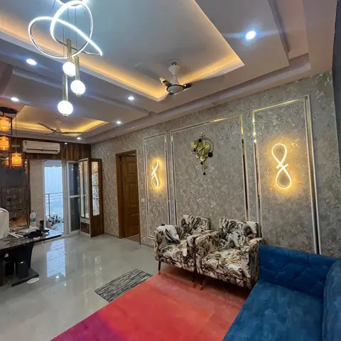 Living room with a cove-lit tray ceiling, mirror-framed textured wall panels with infinity LED sconces, a blue tufted sofa