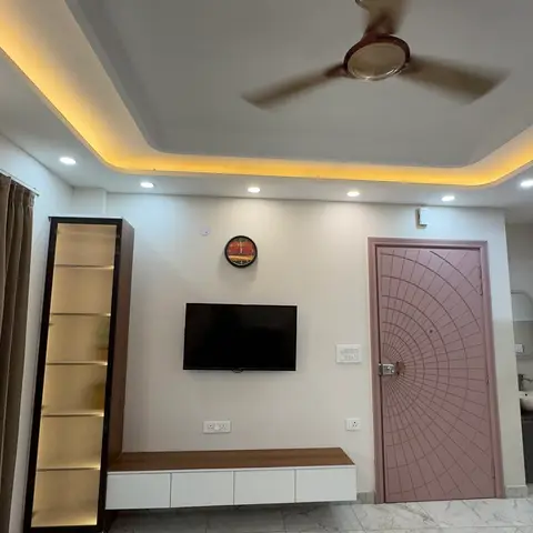 Living room with a cove-lit stepped false ceiling, a floating two-tone TV console, a tall fluted-glass display cabinet