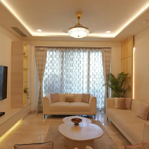 Living room with a crystal ceiling-fan chandelier, sheer patterned curtains, twin cream sofas around a two-piece stone coffee table