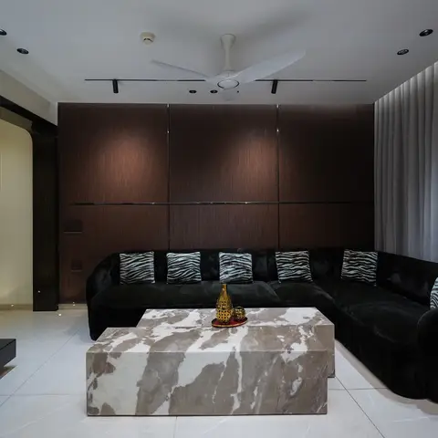 Living room with a curved black velvet sectional sofa styled with zebra-print cushions, a dark wood fluted panelling backdrop
