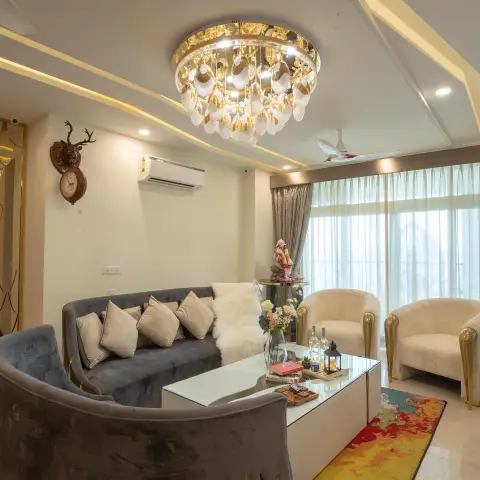 Living room with a curved grey velvet sofa and gold-trimmed cream barrel chairs around a mirrored coffee table