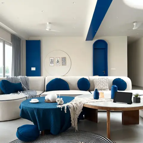 Living room with a curved white sofa dressed in cobalt blue round cushions, an arched blue-painted internal door