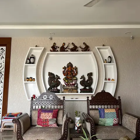 Living room with a curved white display niche holding a brass Ganesha idol and vases