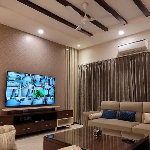 Living room with a damask-wallpapered TV wall, an exposed wood beam ceiling, heavy taupe curtains