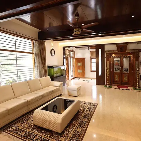 Living room with a dark wood beamed ceiling and pendant fan, a cream leather sectional sofa, a patterned area rug and glass-top coffee table