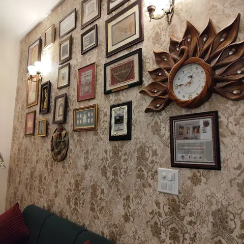 Living room with a densely curated gallery wall of framed art and a wood peacock-shaped clock over damask wallpaper