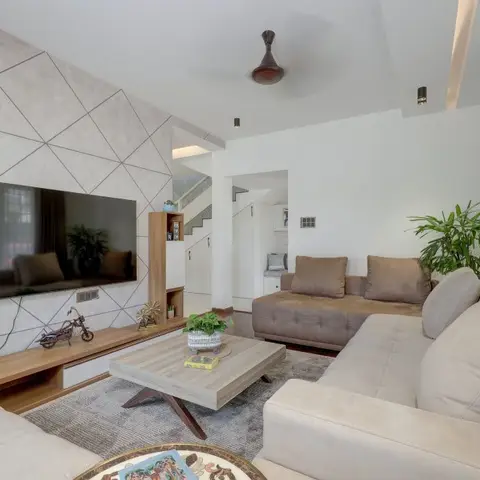 Living room with a diamond-pattern textured stone TV feature wall, a wood-toned open console, an X-leg wooden coffee table, and beige-and-taupe sectional sofas.