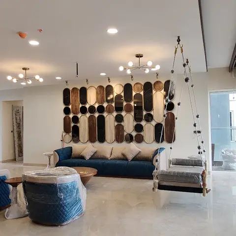 Living room with a dramatic capsule-shaped wood-and-mirror wall art installation, a navy velvet sofa, a hanging swing chair, and dual sputnik chandeliers