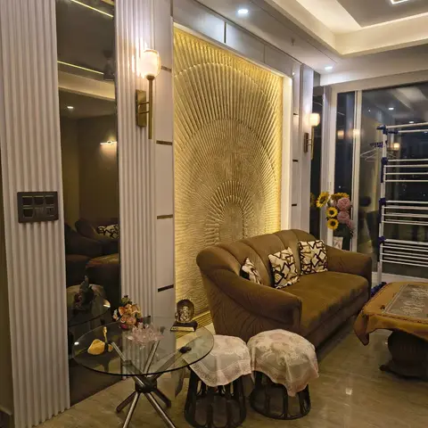 Living room with a dramatic gold sunburst-textured feature wall flanked by mirrored fluted pilasters, brass wall sconces, a cove-lit ceiling