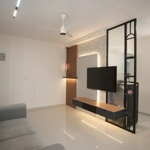 Living room with a floating black-and-wood TV console against a backlit floral wallpaper panel, flanked by a black metal-framed fluted glass partition.
