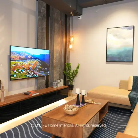 Living room with a floating, under-lit wood TV console set against a stone-clad pillar, a tan sectional sofa with teal throw, and a navy striped rug.