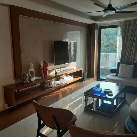 Living room with a floating wood TV console beneath a stone-clad accent wall, a marble floor