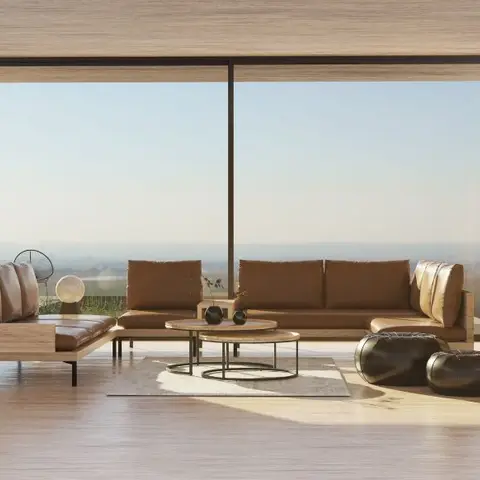 Living room with a floor-to-ceiling glass wall framing an open horizon view, a tan leather L-shaped sofa around nesting round coffee tables