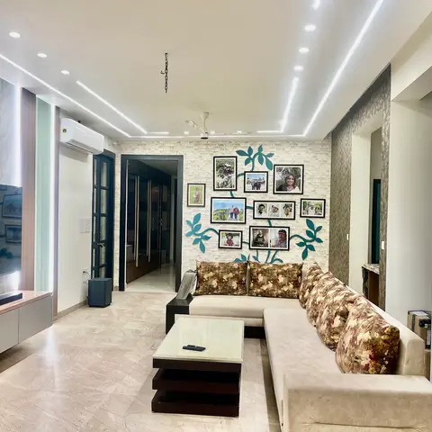 Living room with a floral L-shaped sofa facing a stone-clad accent wall decorated with a family-photo tree art installation.