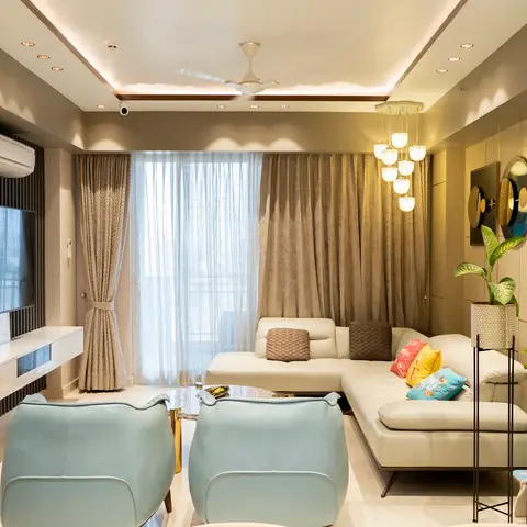 Living room with a fluted-panel TV feature wall, cream L-shaped sofa with colorful cushions, pastel blue leather armchairs, a cluster bubble chandelier