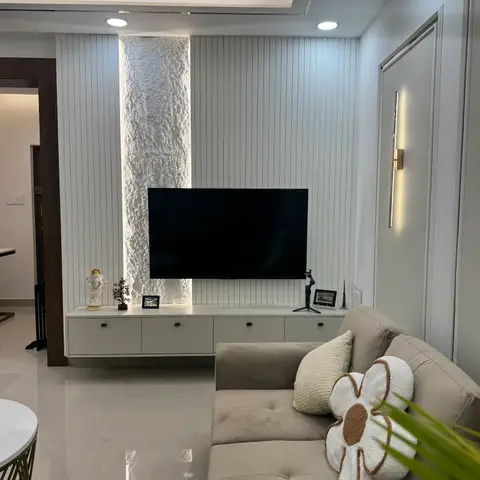 Living room with a fluted panel TV wall featuring a backlit textured stone strip, a floating white console, cove-lit ceiling
