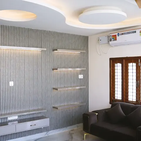 Living room with a fluted stone-panelled TV wall lined by backlit floating shelves under a circular cove-lit false ceiling