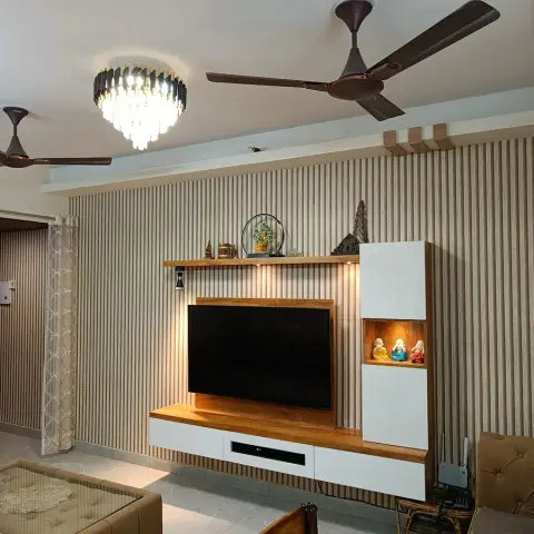 Living room with a fluted wood-slat feature wall behind a floating TV console with a backlit display niche holding three laughing Buddha figurines