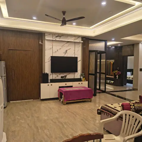 Living room with a fluted wood-panelled wall, marble-clad TV feature wall and cove-lit POP ceiling