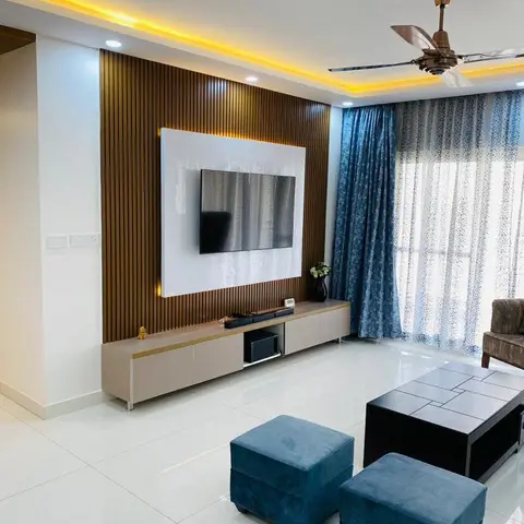 Living room with a fluted wood TV feature wall, cove-lit ceiling, blue patterned curtains and matching velvet ottomans