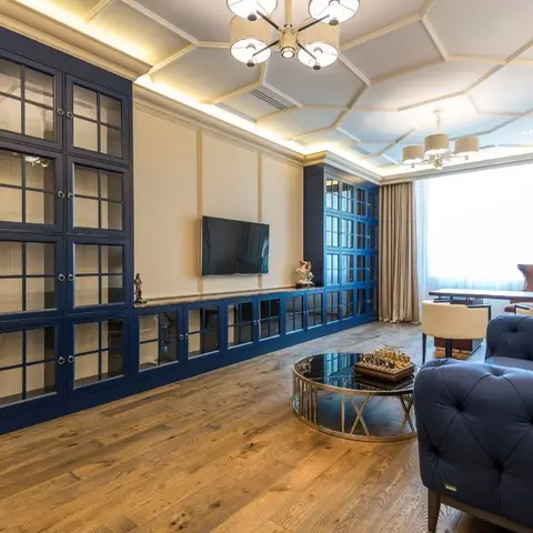 Living room with a full-wall navy glazed display cabinetry run, a hexagonal coffered false ceiling with a brass pendant, and a tufted navy Chesterfield sofa.