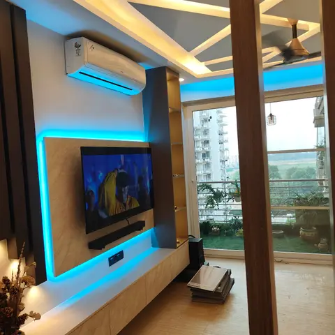 Living room with a geometric cove-lit false ceiling, a marble-panel TV unit trimmed in blue LED strip lighting