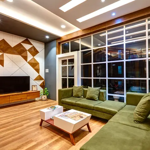 Living room with a geometric wood-and-tile triangle feature wall behind a floating TV console, an olive-green L-shaped sofa, nested white coffee tables