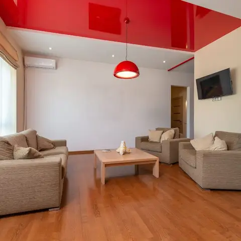 Living room with a glossy red lacquered ceiling drop and matching red dome pendant over beige sofas on a wood floor.