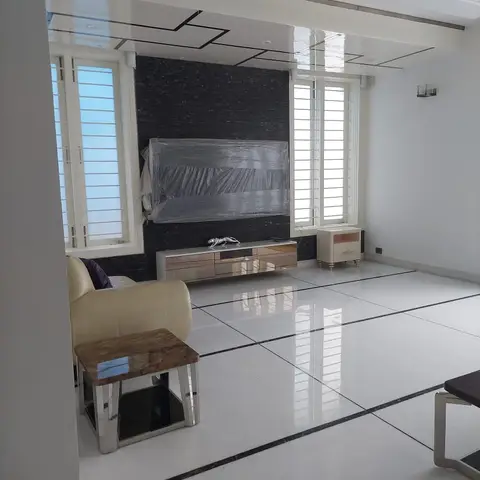Living room with a glossy stepped ceiling, a black textured-stone TV wall, and a mirrored glass TV console