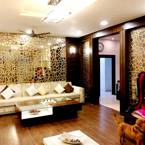Living room with a gold mirrored geometric jaali partition wall, a cream tufted sofa, a glass-top storage coffee table