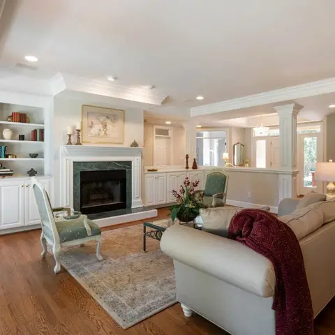 Living room with a green marble fireplace surround flanked by built-in bookshelves, a pair of upholstered wingback chairs