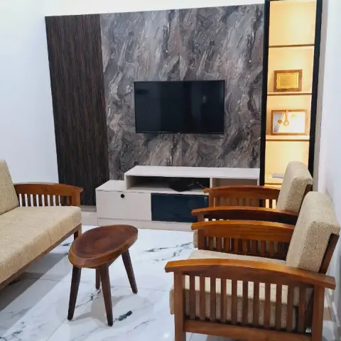 Living room with a grey-brown marble-look TV panel between a dark fluted strip and a black-framed lit column displaying trophies