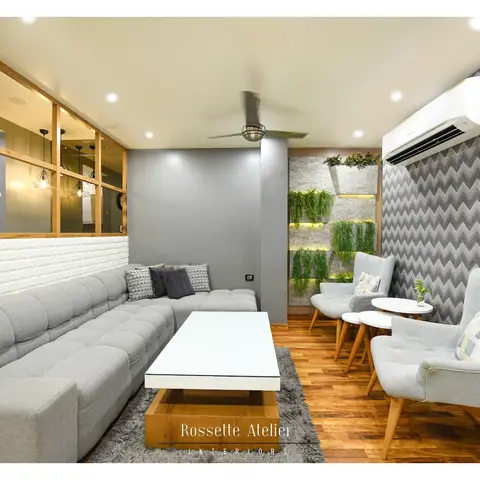 Living room with a grey chevron-patterned accent wall and a vertical planted wall niche beside mid-century wingback chairs