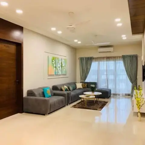 Living room with a grey L-sofa and teal cushions set against a full-height teak veneer wall of flush concealed doors, a floral diptych alongside