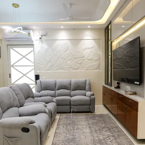 Living room with a grey reclining sofa set, a 3D carved leaf relief mural repeated on the wall and TV backdrop, and a wood-and-white floating TV console.