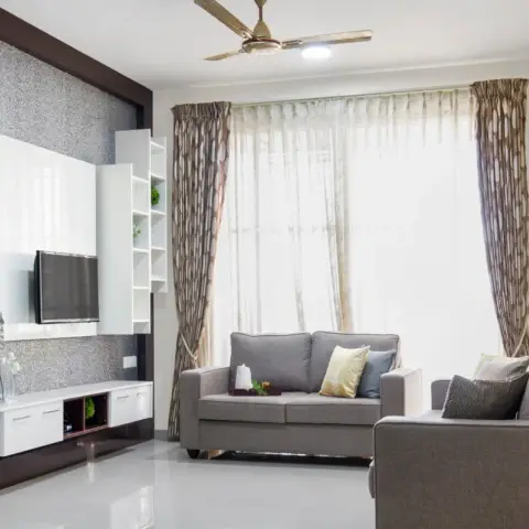 Living room with a grey sofa set, a textured wallpaper TV feature wall with white gloss panelling and floating shelves
