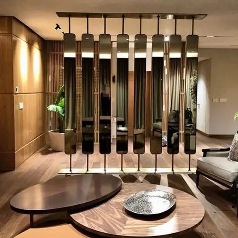 Living room with a hanging smoked-mirror panel screen dividing the space from the dining area, set against a wood-slat wall and nested round coffee tables.