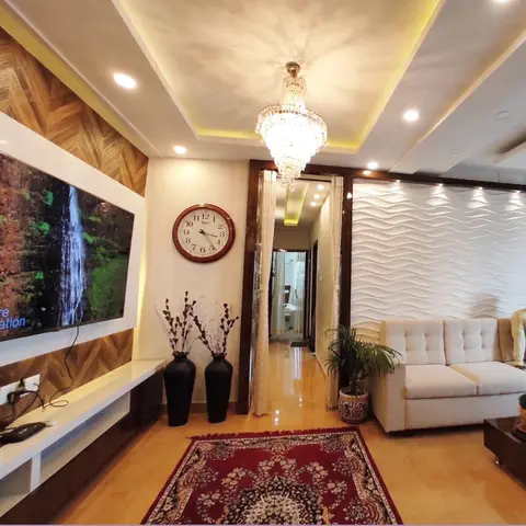 Living room with a herringbone wood accent wall behind the TV, a crystal chandelier in a cove-lit tray ceiling