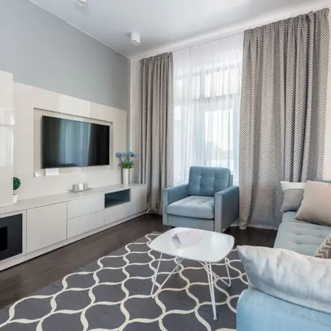 Living room with a high-gloss white TV wall unit and open display shelving, floor-length chevron-patterned curtains