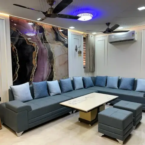 Living room with a large backlit agate-pattern resin wall art panel, panel-moulded walls, a blue-grey tufted L-sofa