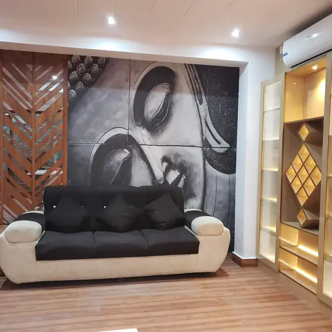 Living room with a large black-and-white Buddha-face wall mural, a wood chevron jaali partition screen