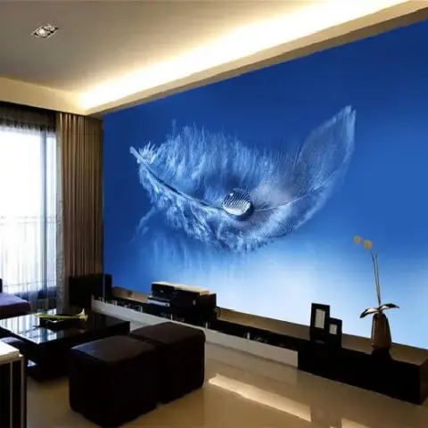 Living room with a large blue feather-mural wallpaper accent wall behind a low black TV console and dark ottoman seating.